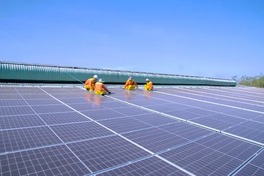 Representative image of technicians installing photovoltaic panels on an industrial rooftop.